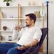 Man sitting down and receiving hydration IV therapy while drinking a glass of water