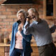 Older couple in their kitchen using kitchen utensils as microphones and singing