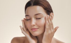 Up close image of model showing off her skin while touching her face