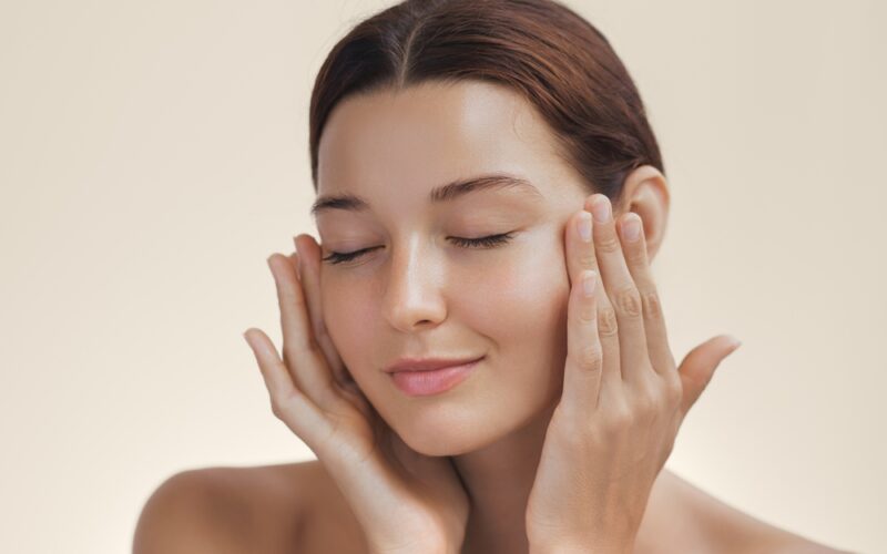 Up close image of model showing off her skin while touching her face