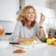 Woman smiling at camera while eating fruits in the kitchen
