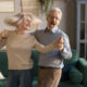Happy and active older couple dancing in their living room