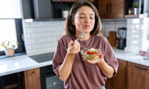Young woman eating a small healthy meal in her kitchen