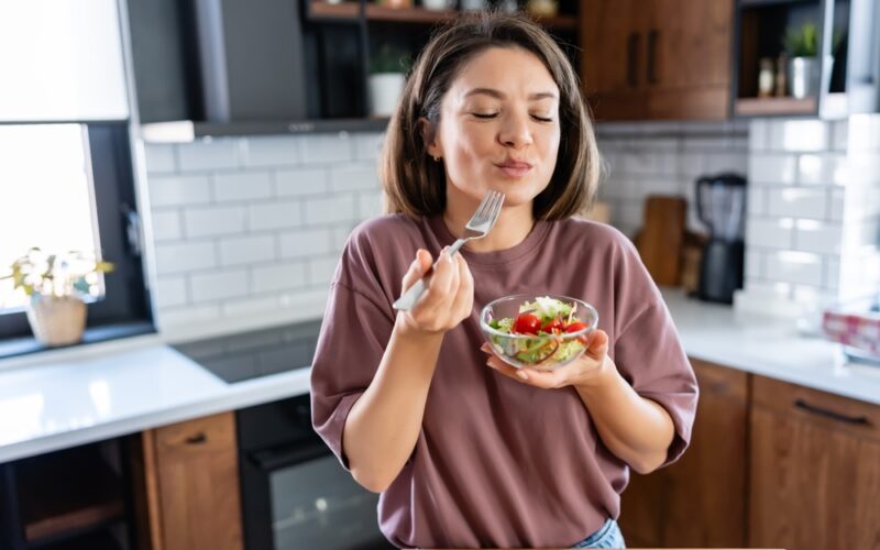 Young woman eating a small healthy meal in her kitchen