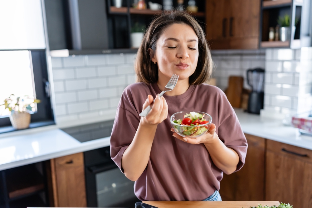 Young woman eating a small healthy meal in her kitchen