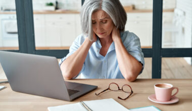 Tired and fatigued older woman sitting at her computer