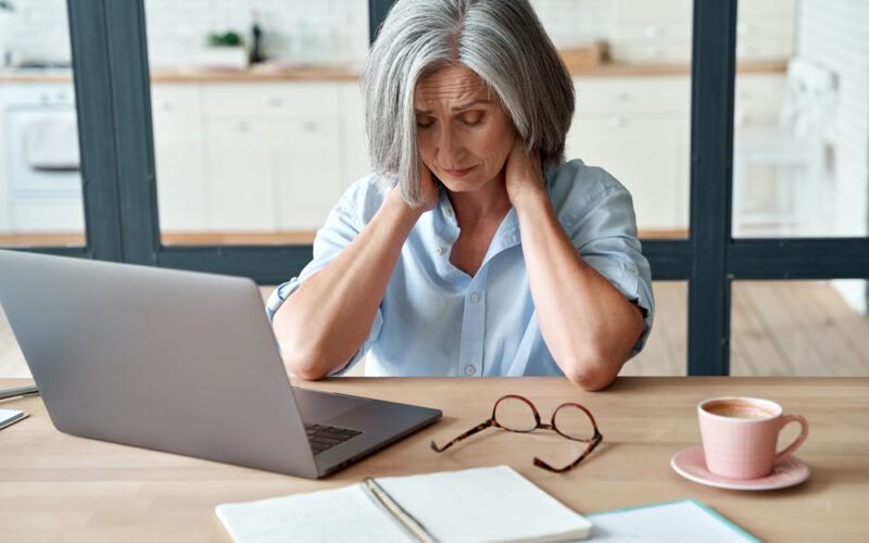Tired and fatigued older woman sitting at her computer