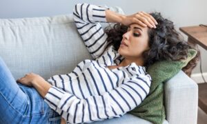 Woman laying down on the couch, stressed out and deep in thought