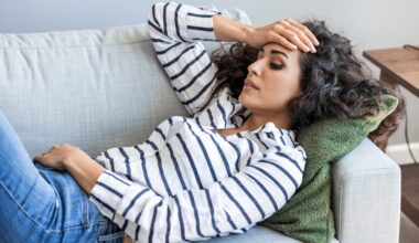 Woman laying down on the couch, stressed out and deep in thought