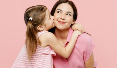 A young girl hugging an adult woman, both wearing pink, against a pink background.