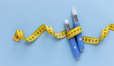 Two injectors dosing pens for subcutaneous injection of antidiabetic medication or anti-obesity medication hovering over a blue background. Yellow measuring tape around the injectors. antidiabetic