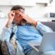 Tired businessman takes off glasses and feels eye strain from working online with laptop, Caucasian man sits on sofa and rubs his eyes, feels headache and lack of energy