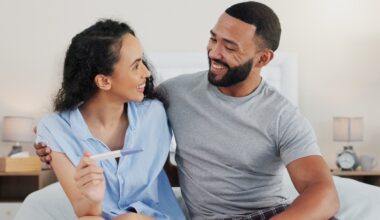 Happy couple, pregnancy stick and results in home, hug and support for positive baby news. People, plastic test and together for reading ovulation tool in bedroom, fertility treatment and embrace