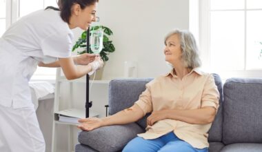 Senior woman with intravenous drip sitting on couch, physician, nurse doctor fixing IV drip infusion, geriatrics hospital eldercare, therapy to infuse vitamins, chemotherapy to maintain health clinic