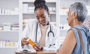Pharmacist explaining medication to a patient while holding a prescription bottle, providing guidance on dosage and discussing liraglutide cost.