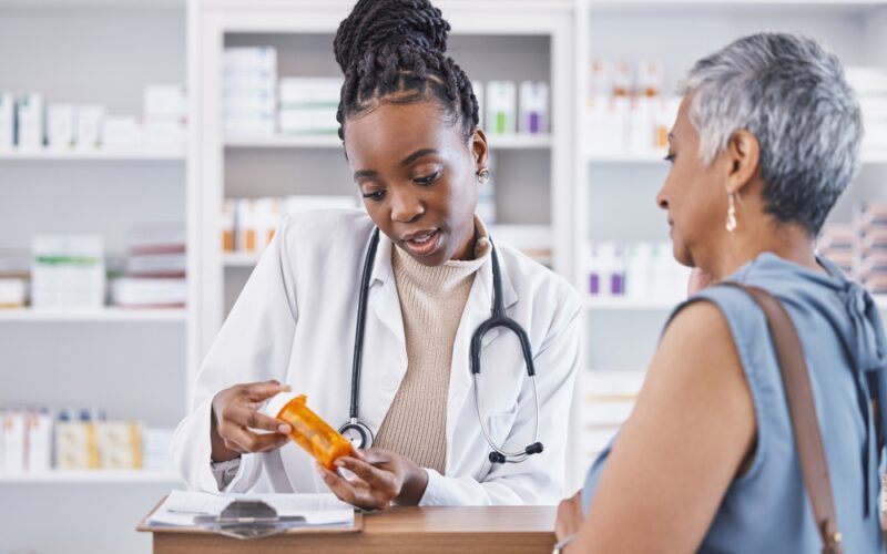 Pharmacist explaining medication to a patient while holding a prescription bottle, providing guidance on dosage and discussing liraglutide cost.