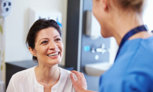 Female Patient Being Reassured By Doctor In Hospital Room