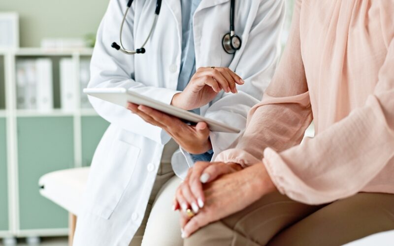 Pharmacist explaining medication to a patient while holding a prescription bottle, providing guidance on dosage and discussing liraglutide cost.