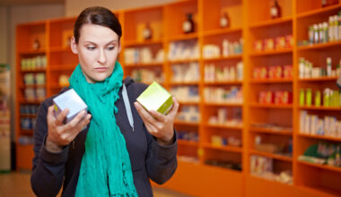 Woman in a pharmacy comparing two medication boxes, symbolizing patient decisions when choosing between semaglutide and liraglutide