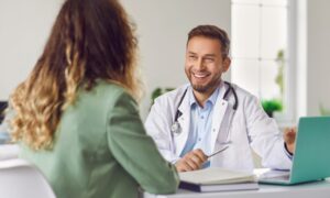 Smiling doctor consulting with a patient in his office, discussing treatment options and explaining the liraglutide maximum dose.