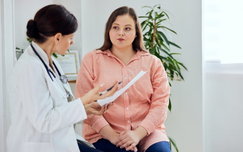 Doctor reviewing medical notes with a patient during consultation, evaluating whether she is a suitable liraglutide candidate for treatment.