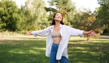 Happy woman standing outdoors with open arms and eyes closed, enjoying fresh air and sunlight — representing freedom, confidence, and the positive results of a successful semaglutide weight loss journey.