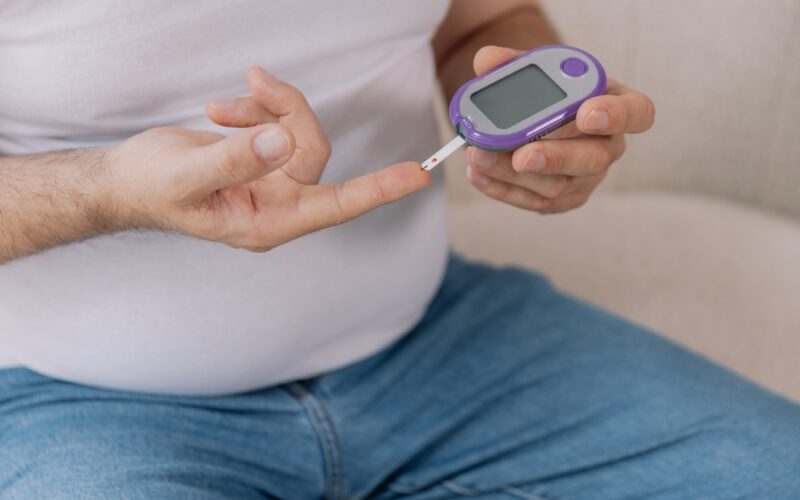 Diabetic senior man on wheelchair checking blood sugar level with fingerstick testing glucose meter. Elderly man with type 1 diabetes using blood glucose monitor at home. Acarbose and Metformin