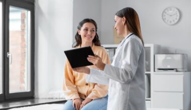 medicine, healthcare and people concept - female doctor with tablet pc computer talking to smiling woman patient at hospital