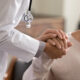 Doctor giving hope. Close up shot of young female physician leaning forward to smiling elderly lady patient holding her hand in palms. Woman caretaker in white coat supporting encouraging old person. How to talk to your doctor about perimenopause symptoms and treatment goals