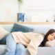 Asian woman resting at home on couch, feeling exhausted after work, lacking energy, or overworked, too tired, and lacking motivation