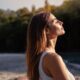 Young woman with long hair enjoying sun with closed eyes getting natural vitamin D outdoors. Peace of mind. Mindfulness, mental health, spirituality, well-being, unwind yourself. Sermorelin Dosage