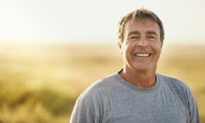 Senior man, smile and portrait at field in summer for outdoor adventure, nature and holiday. Sunshine, happy and face of person by mockup space for weekend vacation, peace and tourism in Turkey