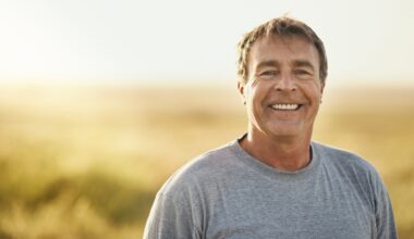 Senior man, smile and portrait at field in summer for outdoor adventure, nature and holiday. Sunshine, happy and face of person by mockup space for weekend vacation, peace and tourism in Turkey