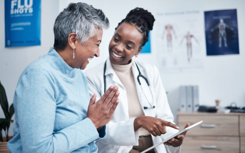 Black woman, doctor and elderly patient with good news, tablet and results for health, advice and report. Happy african medic, mobile touchscreen or healthcare with smile, tech or support in hospital