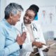Black woman, doctor and elderly patient with good news, tablet and results for health, advice and report. Happy african medic, mobile touchscreen or healthcare with smile, tech or support in hospital
