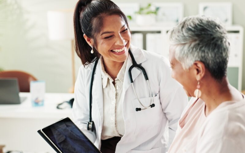 Smiling doctor discussing starting acarbose with a patient during a medical consultation.