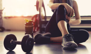 Woman tirzepatide exercise workout in gym fitness breaking relax holding apple fruit after training sport with dumbbell and protein shake bottle healthy lifestyle bodybuilding, Athlete builder muscles lifestyle.