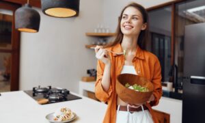 Woman enjoying a healthy salad as part of preparing for an NAD+ IV therapy session, highlighting the importance of light, balanced meals and proper nutrition before infusion for better energy and comfort.