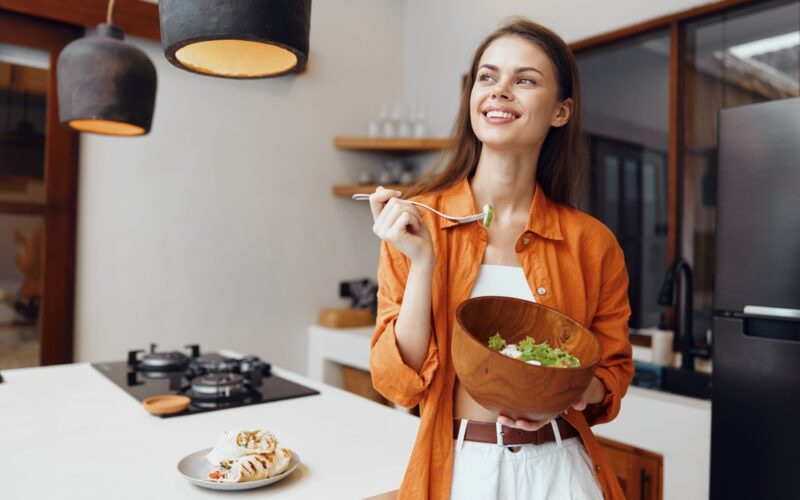 Woman enjoying a healthy salad as part of preparing for an NAD+ IV therapy session, highlighting the importance of light, balanced meals and proper nutrition before infusion for better energy and comfort.