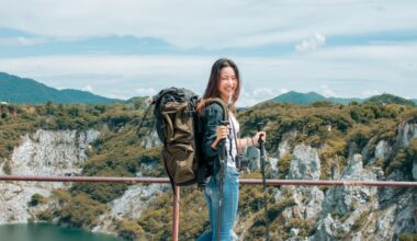 Smiling woman with a large hiking backpack and trekking poles standing on a scenic overlook, representing the role of active lifestyle choices in supporting tirzepatide’s effectiveness for weight management.