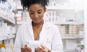 Tirzepatide Woman, pharmacist and checking box with medication, side effects or symptoms at pharmacy. Young African, female person or medical employee reading expiry date on pharmaceutical product at store