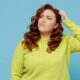 Young puzzled thoughtful confused chubby overweight plus size big fat fit woman wear green sweater look aside scratch head isolated on plain blue background studio portrait. People lifestyle concept Tirzepatide