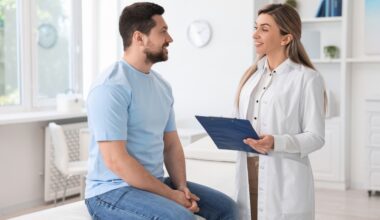Male patient talking with a female doctor holding a clipboard during a consultation, representing medical guidance on vitamin B12 injections and their role in weight management.