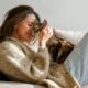 Smiling woman relaxing on a couch with her cat — symbolizing emotional comfort, companionship, and the supportive role of animals in mental well-being.