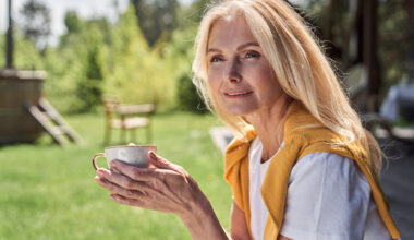 Confident middle-aged woman enjoying coffee outdoors, symbolizing balance and well-being during menopause, representing the discussion on GLP-1 medications and hormone replacement therapy (HRT) for weight management in women over 50.