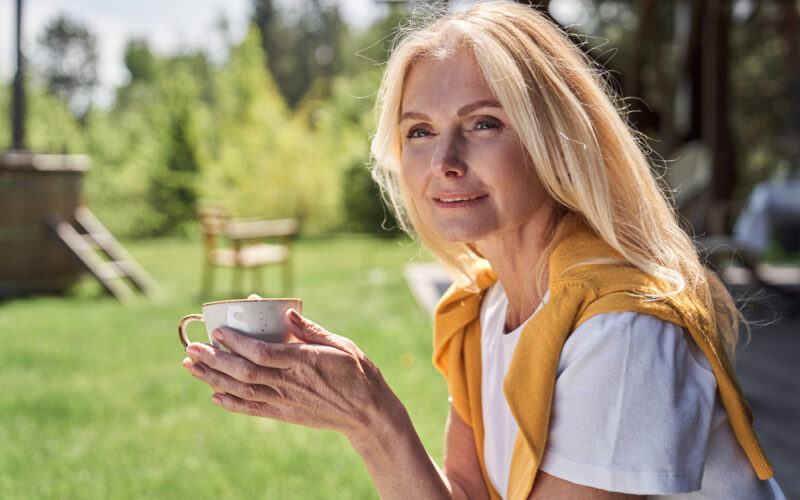 Confident middle-aged woman enjoying coffee outdoors, symbolizing balance and well-being during menopause, representing the discussion on GLP-1 medications and hormone replacement therapy (HRT) for weight management in women over 50.