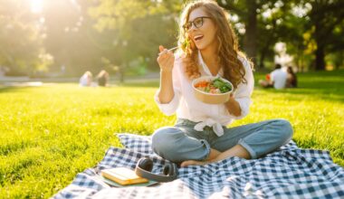 A smiling woman sits on a picnic blanket in a sunny park, eating a healthy bowl of salad. The image represents balanced eating and joyful lifestyle habits that complement Mounjaro (tirzepatide) weight loss treatment.