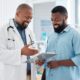 Smiling doctor discusses a treatment plan with a patient while reviewing a medical chart together in a bright clinic — representing supportive healthcare guidance and transparent discussion about medication costs.