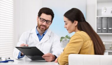 Smiling male doctor showing medical information on a clipboard to a female patient during a consultation, representing professional guidance on oral semaglutide (Rybelsus) dosing and safe weight management.