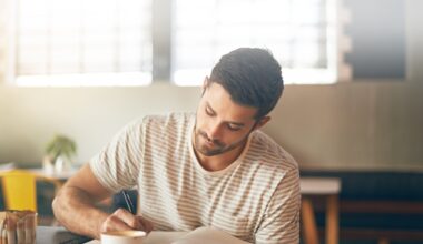 Man sitting at a café writing in a notebook with a thoughtful expression, symbolizing self-reflection and emotional adjustment during a weight-loss journey with GLP-1 medications.